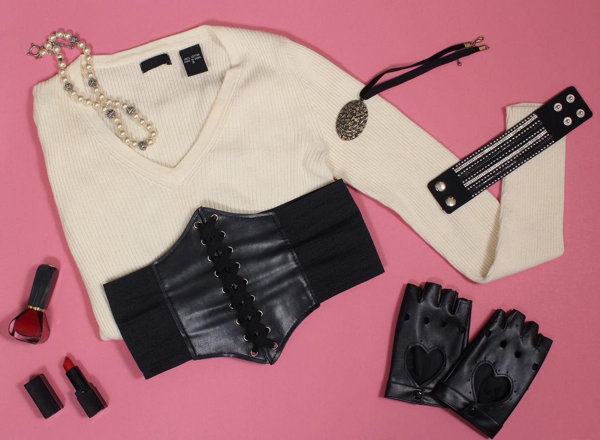 Sweater with corset belt and black leggings on pink background