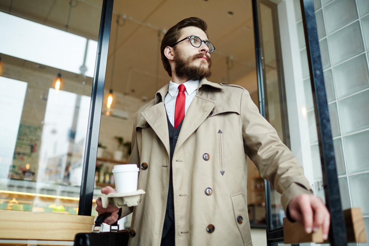 : Well-dressed bearded man with a glass of coffee going out of the cafe after lunch