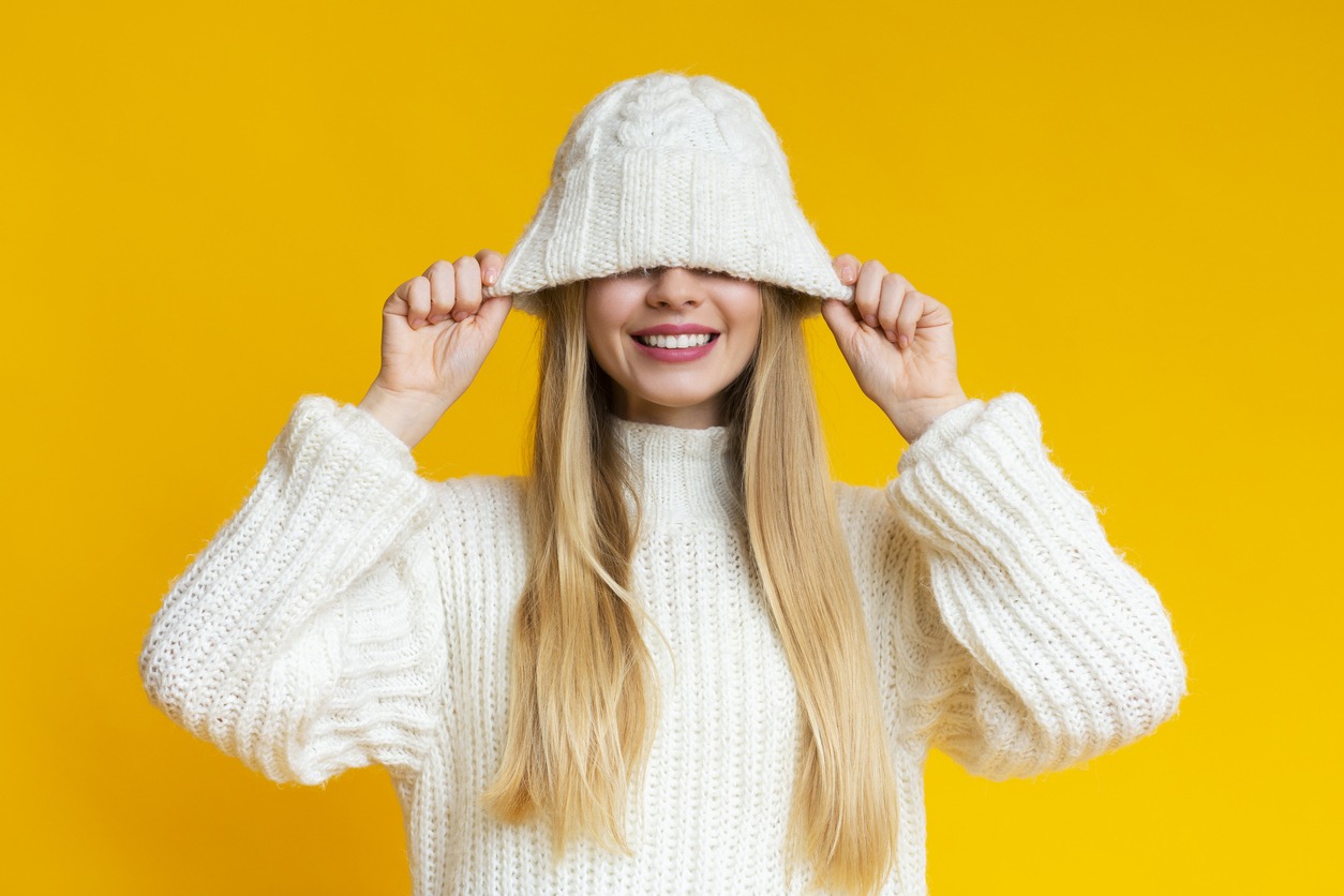 Smiling woman pulling down white woollen hat