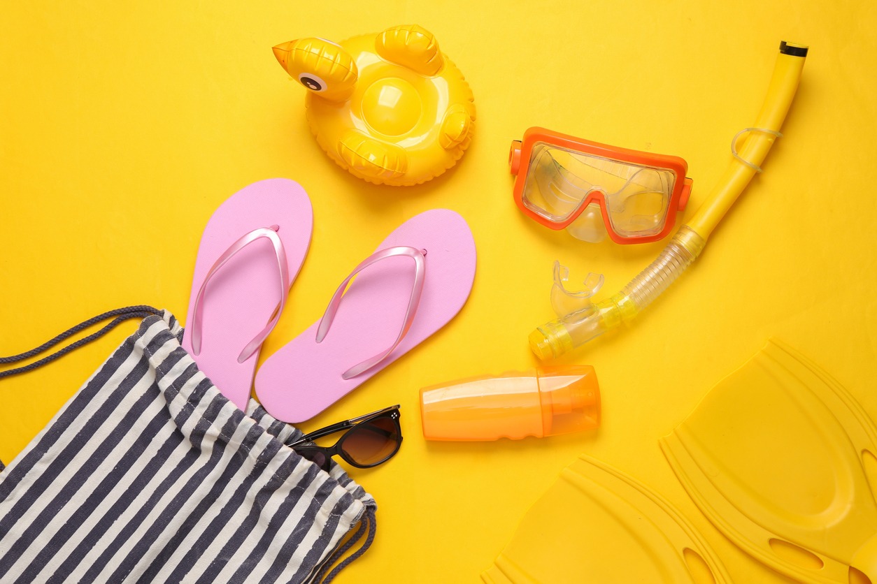 a cotton drawstring beach bag with beach accessories on a yellow background