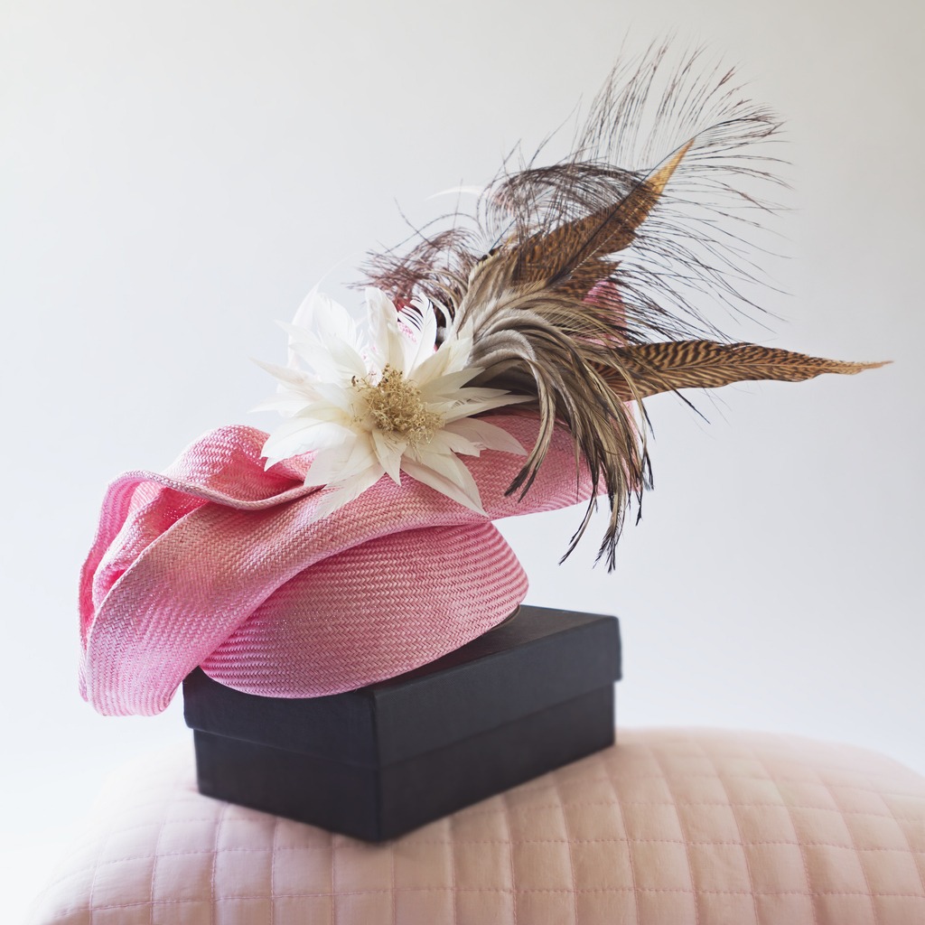 a pink fascinator with feathers and flowers on a box