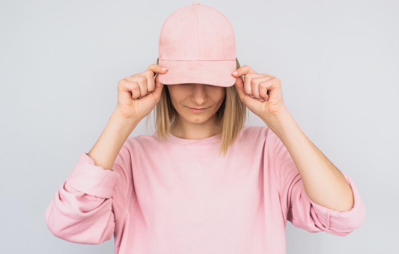 a woman wearing a pink sweater showing off her pink structured cap