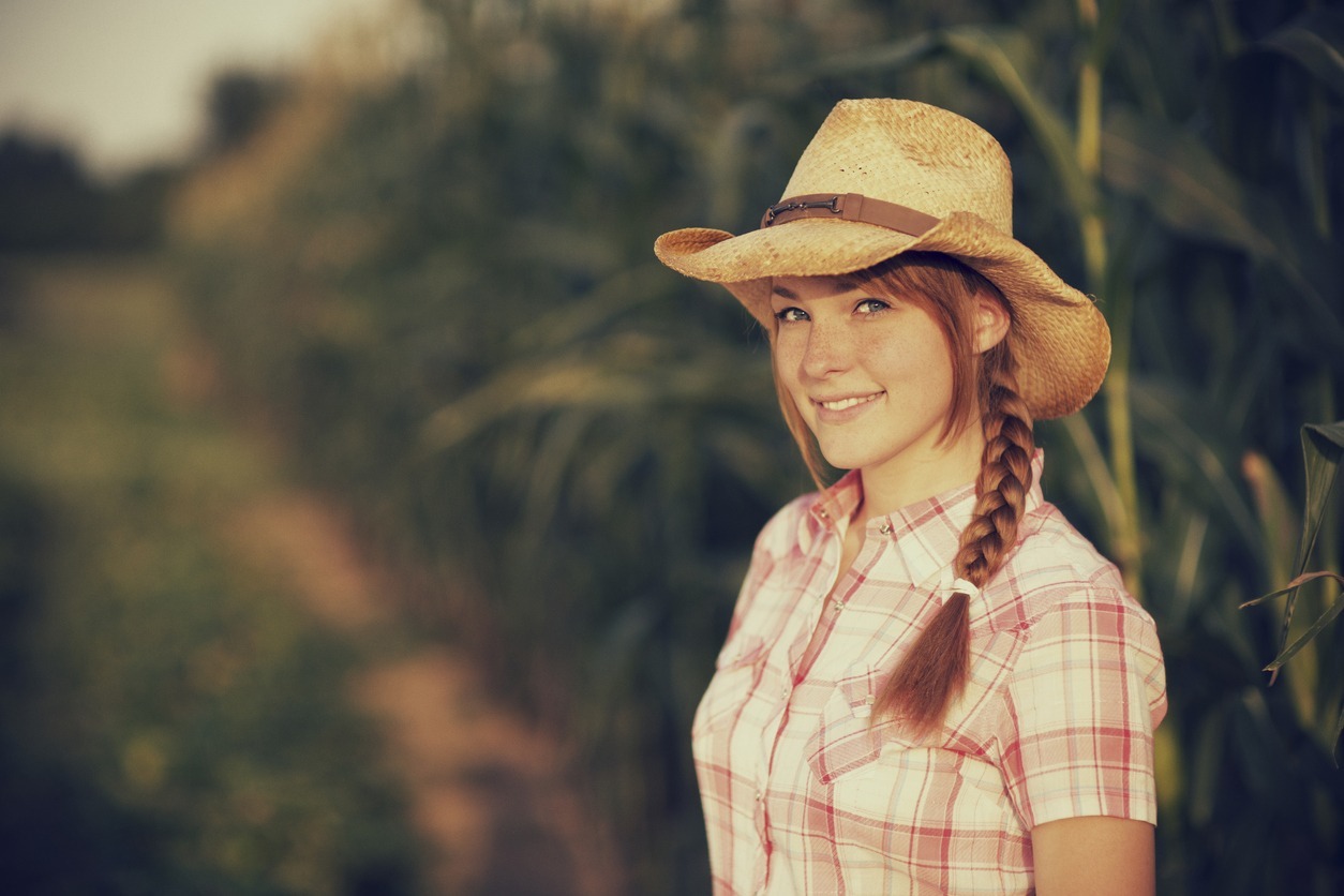a woman with braided hair wearing a straw cowboy hat at the farm