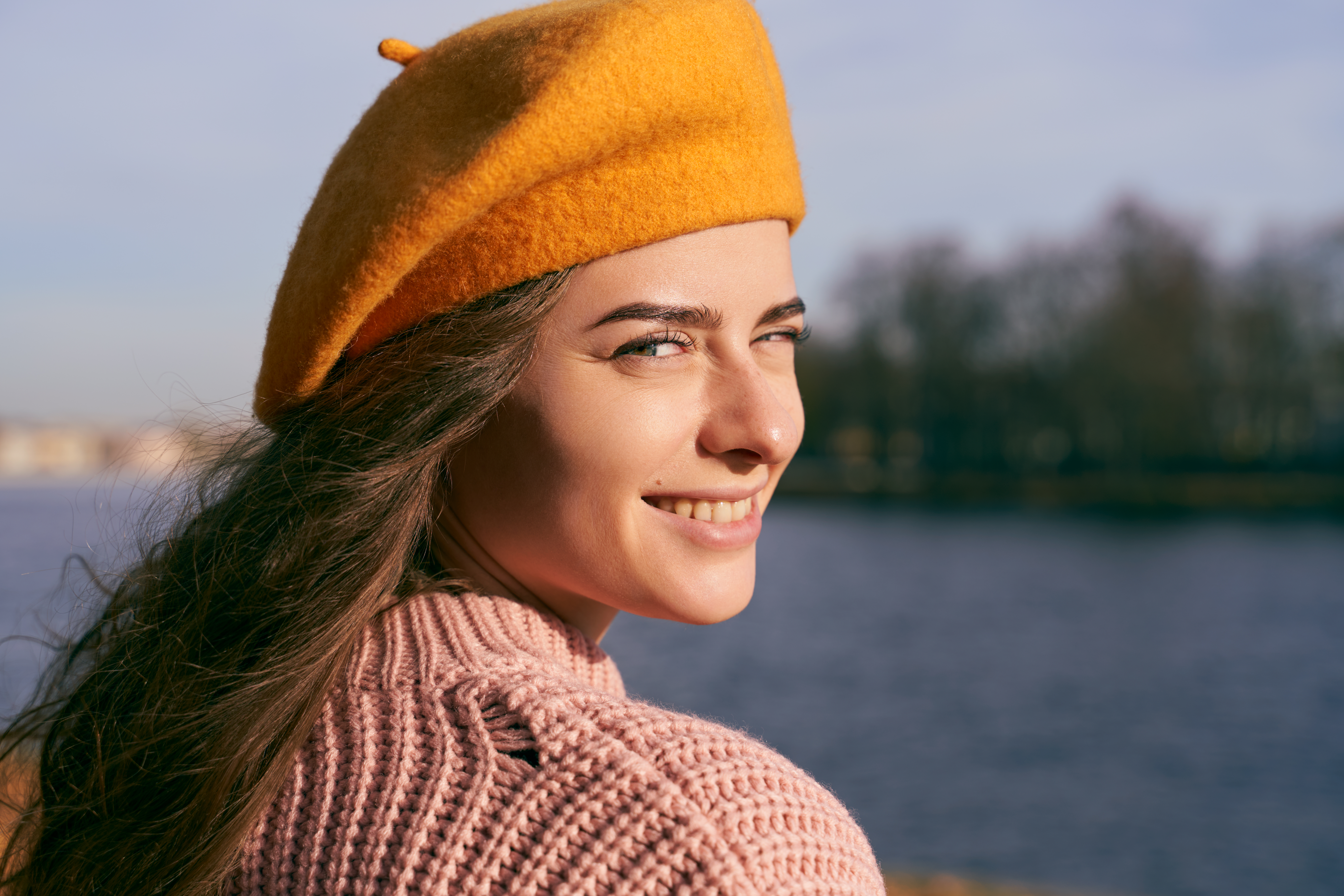 a woman with brown hair and green eyes wearing a pink sweater and yellow beret 