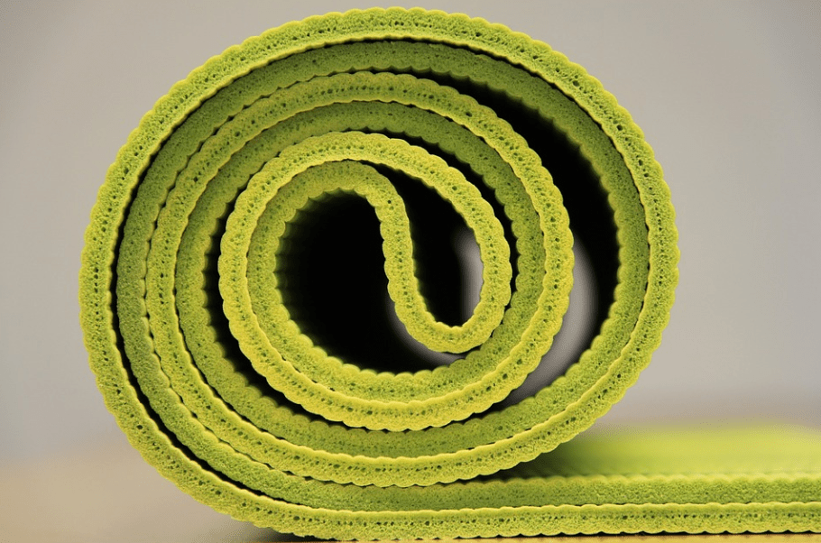 a zoomed in photo of a rolled green yoga mat 