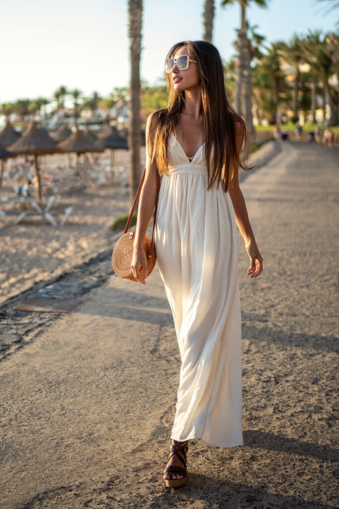a girl wearing a white maxi dress and a round rattan bag