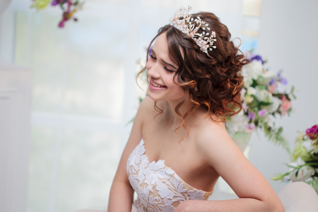 Beautiful girl in a wedding dress sitting and smiling. Bride in luxurious dress, close-up