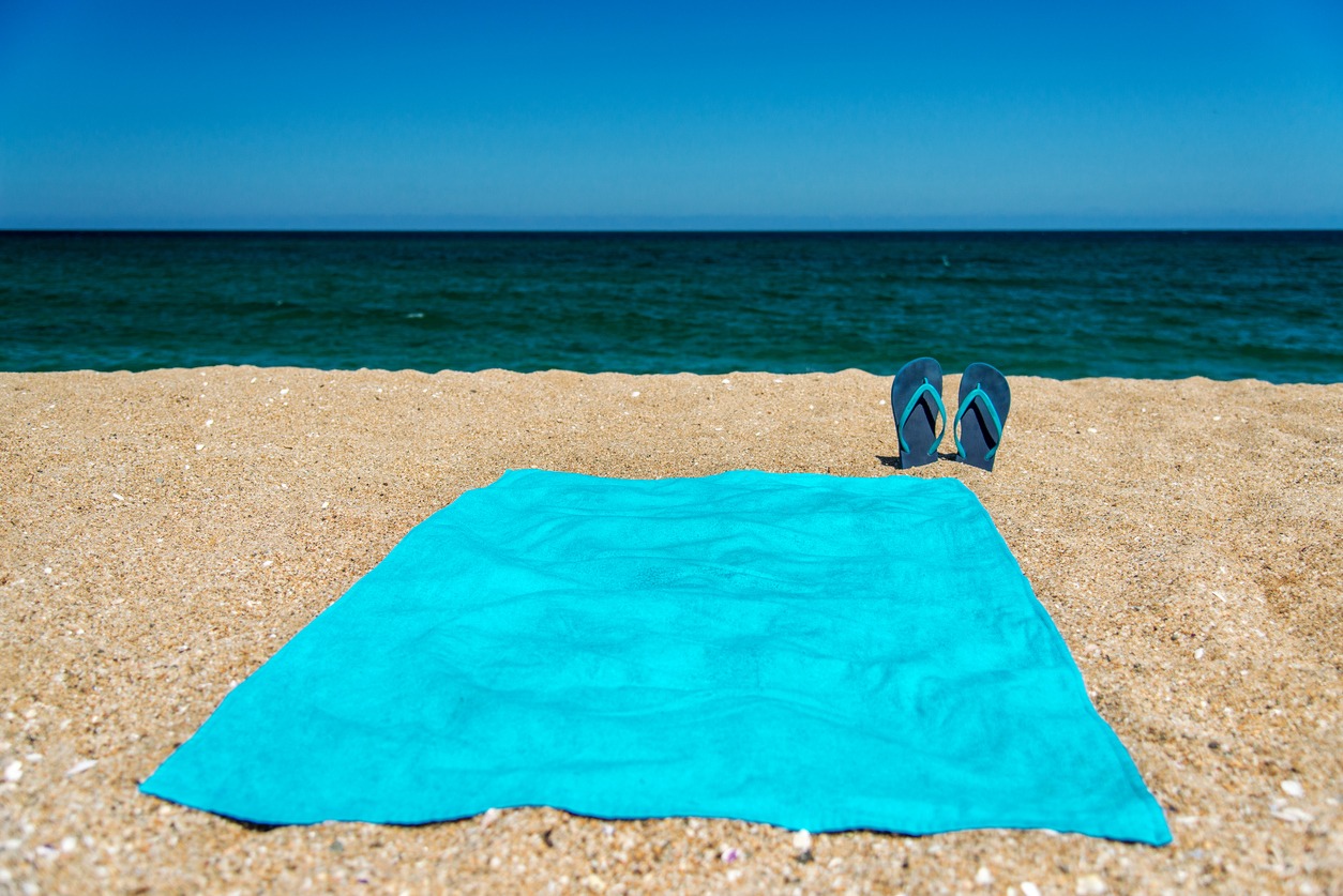 blue flip flops and blue towel on a sand