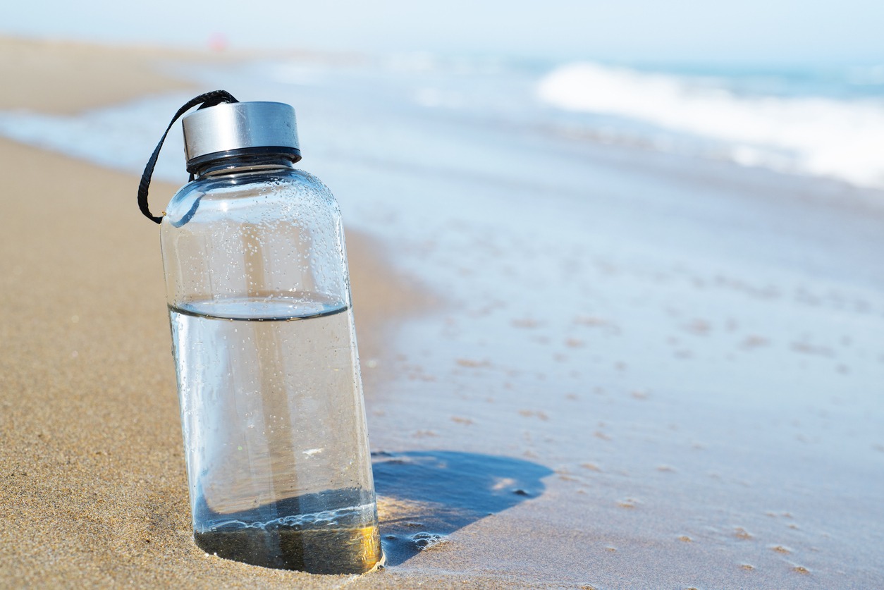 bottle of clean water on a beach's sand.
