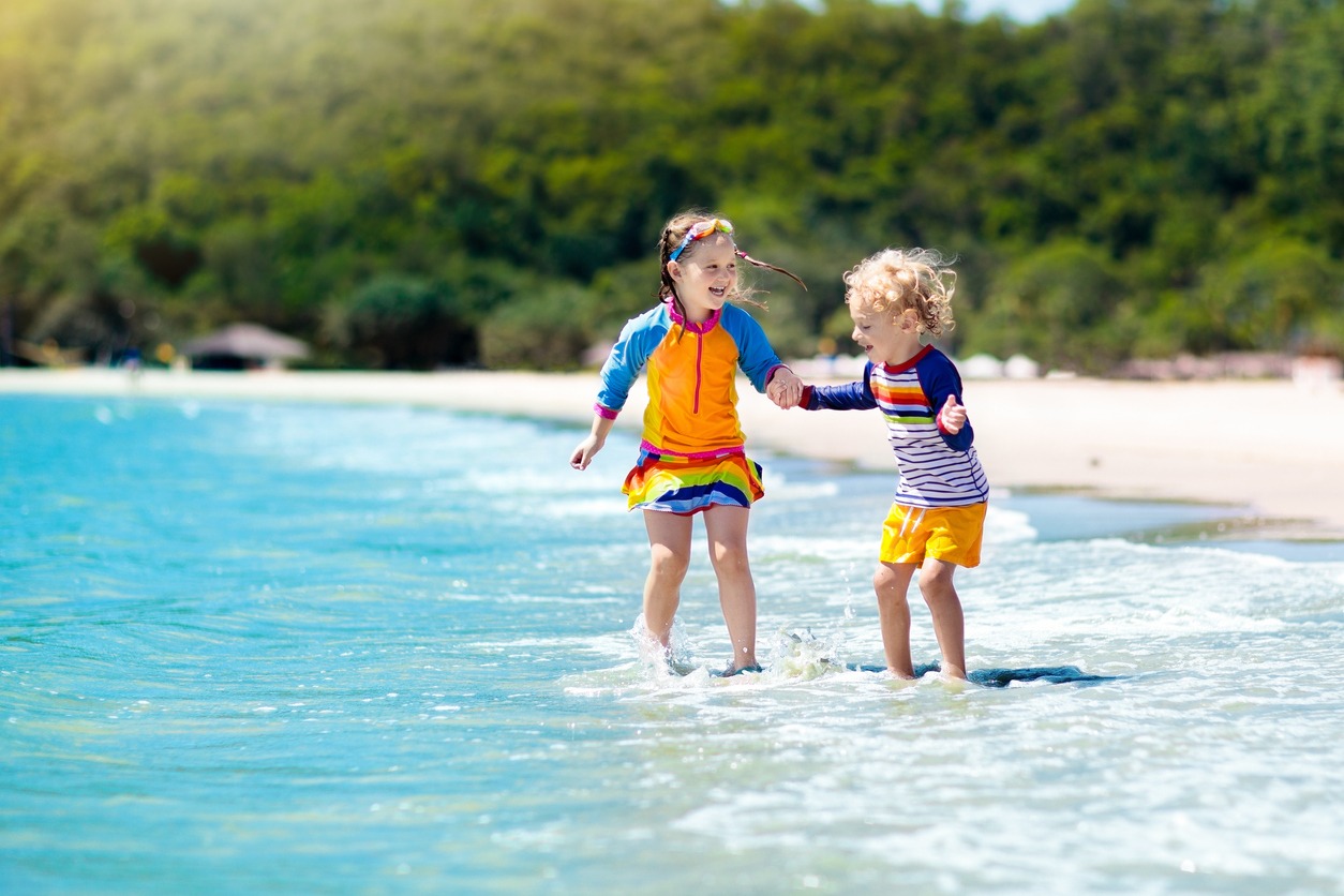 children having fun in the water while sporting colorful rashguards