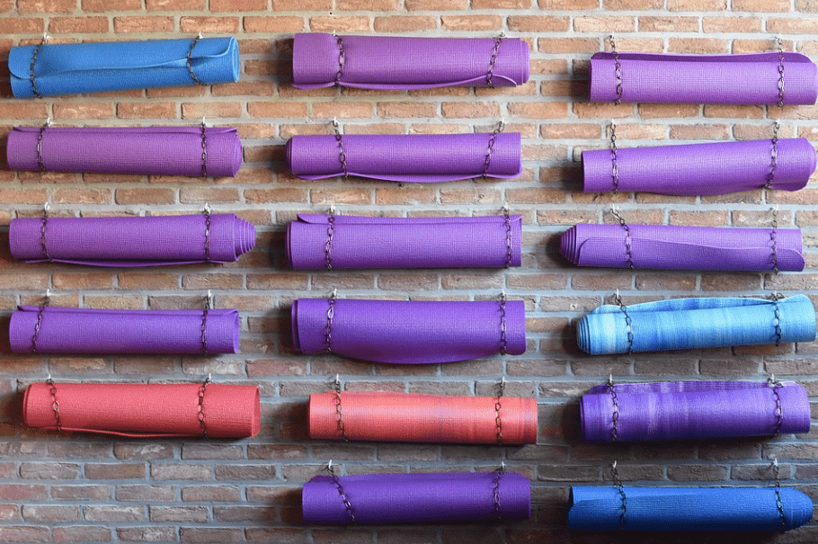 different colored yoga mats chained to a brick wall