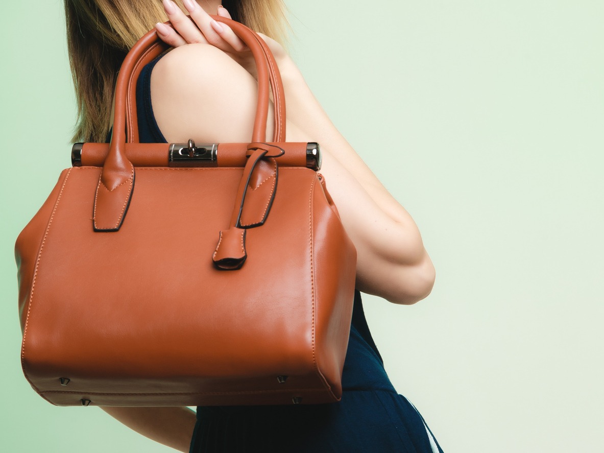 Woman with elegant outfit holding brown leather bag