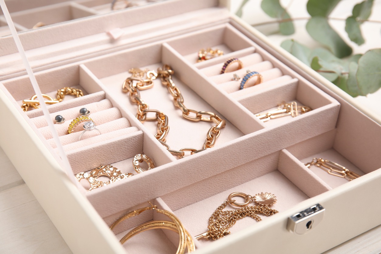 Jewelry box with stylish golden bijouterie on white wooden table, closeup