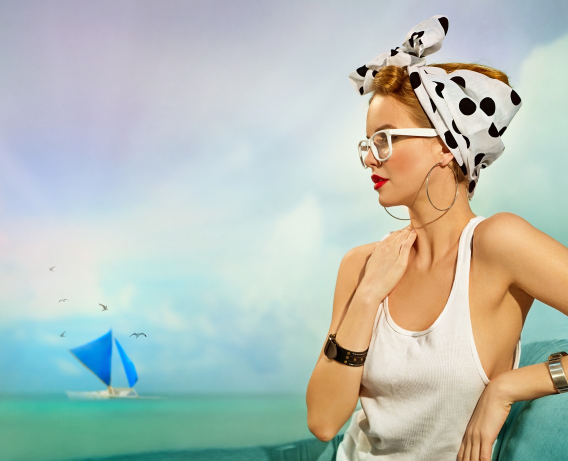 Pin-up girl with a headscarf in white t-shirt sitting by the sea