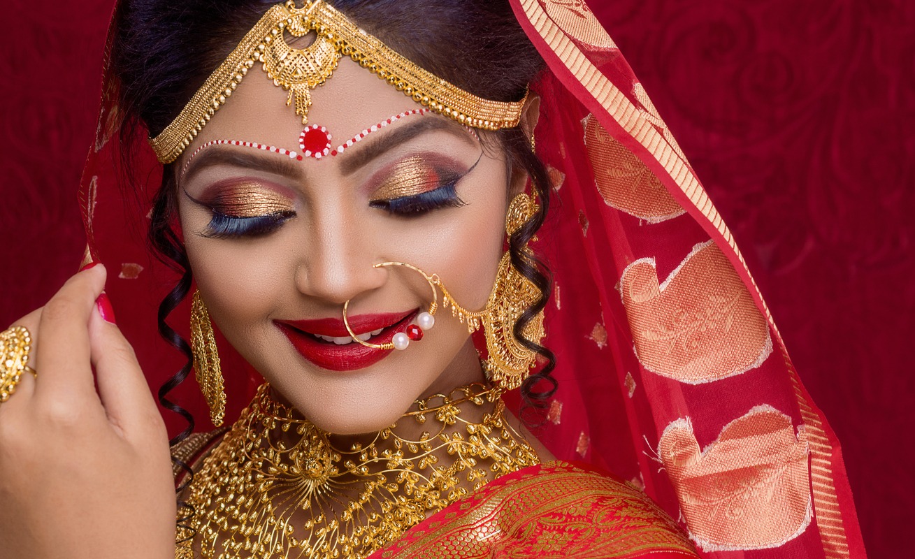 portrait of an Indian bride wearing gold jewelry and a traditional red sari in a Hindu wedding