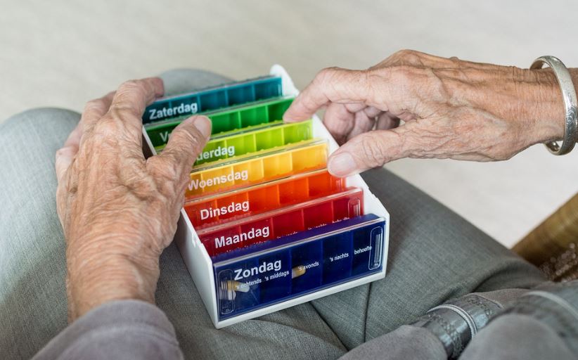 senior holding pillboxes labeled with days of the week in Dutch