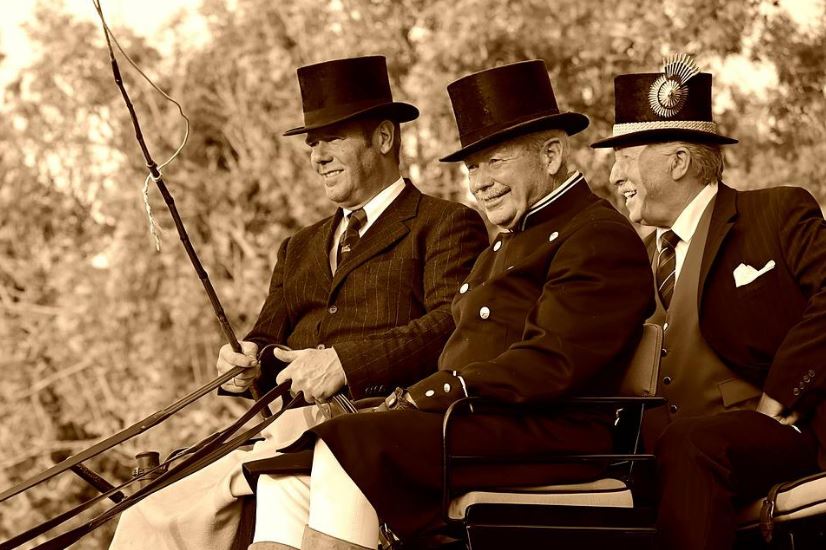three old men in a carriage wearing formal attire and top hats