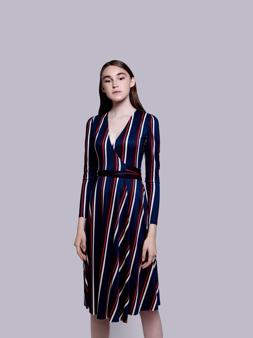 Waist up portrait of beautiful young girl wearing dark blue white and red striped casual knee length dress posing. Looks fresh and lovely Tall fashion model studio portrait on white background Perfect glowing skin Beauty Fitness Healthcare concept