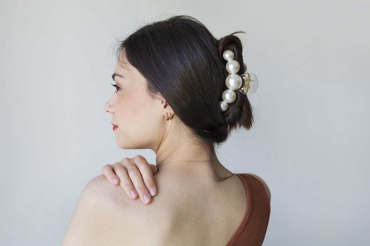 Young woman with beautiful hair clips on grey background