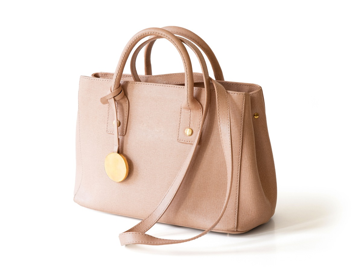 A beige purse that can be worn as a handbag, a shoulder bag, and a crossbody bag