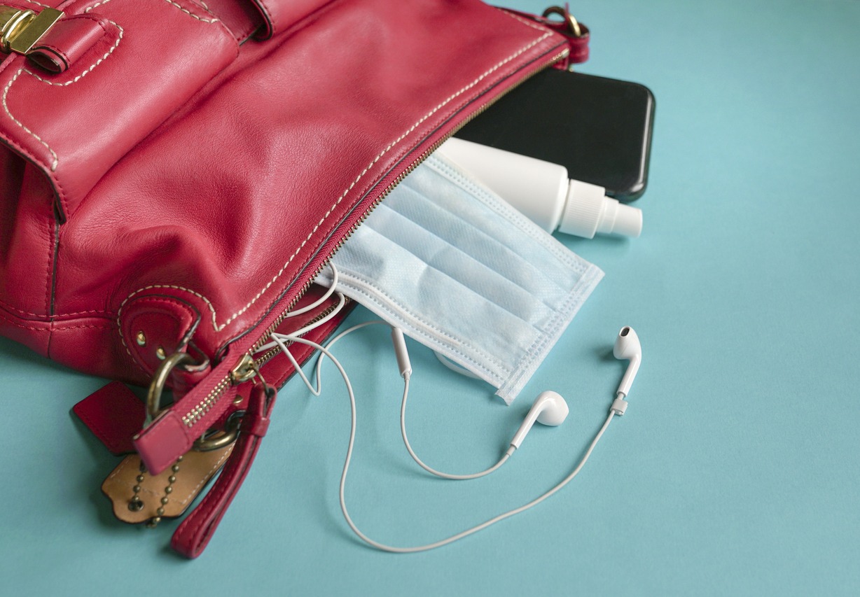 A red handbag with ear phones, phone, hand sanitizer and face mask”
