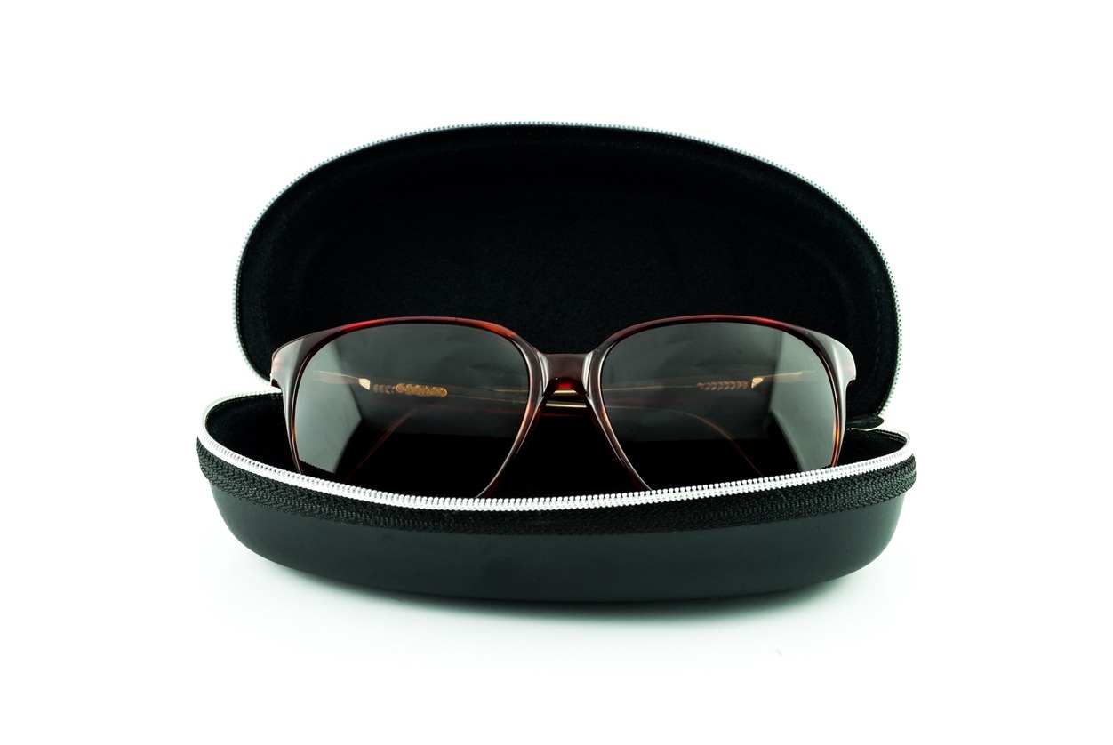 A set of brown sunglasses in a black case on white background