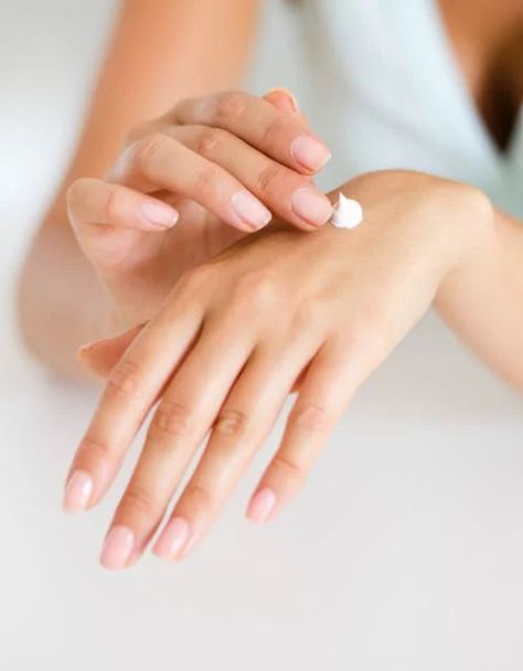 A-woman-applying-cream-to-her-hands