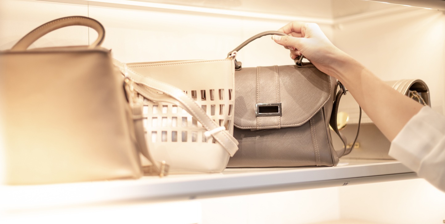 A woman’s hand picking out a leather bag in a department store
