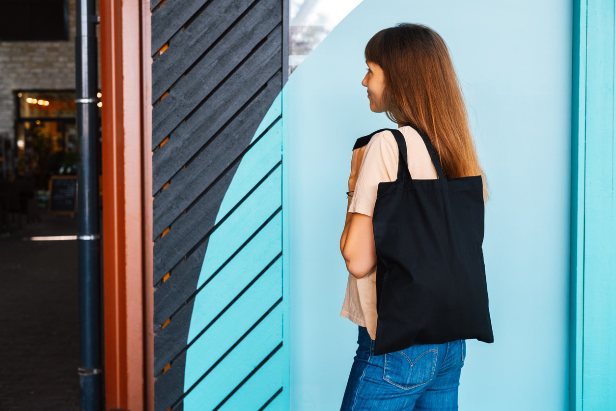 Woman holding black canvas tote bag. Bag mockup for design