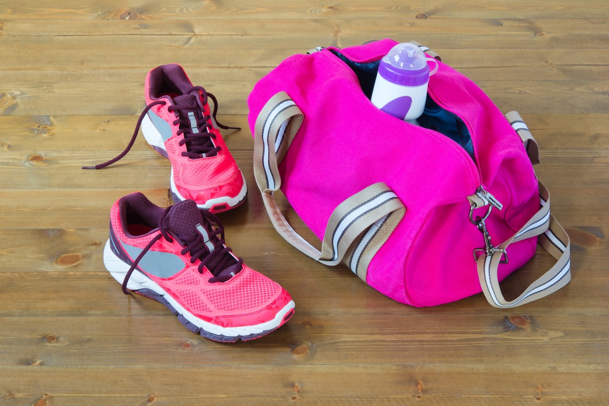 a hot pink gym duffle bag on the floor with a pair of shoes