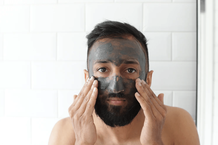 a-person-applying-a-black-mask-on-his-face