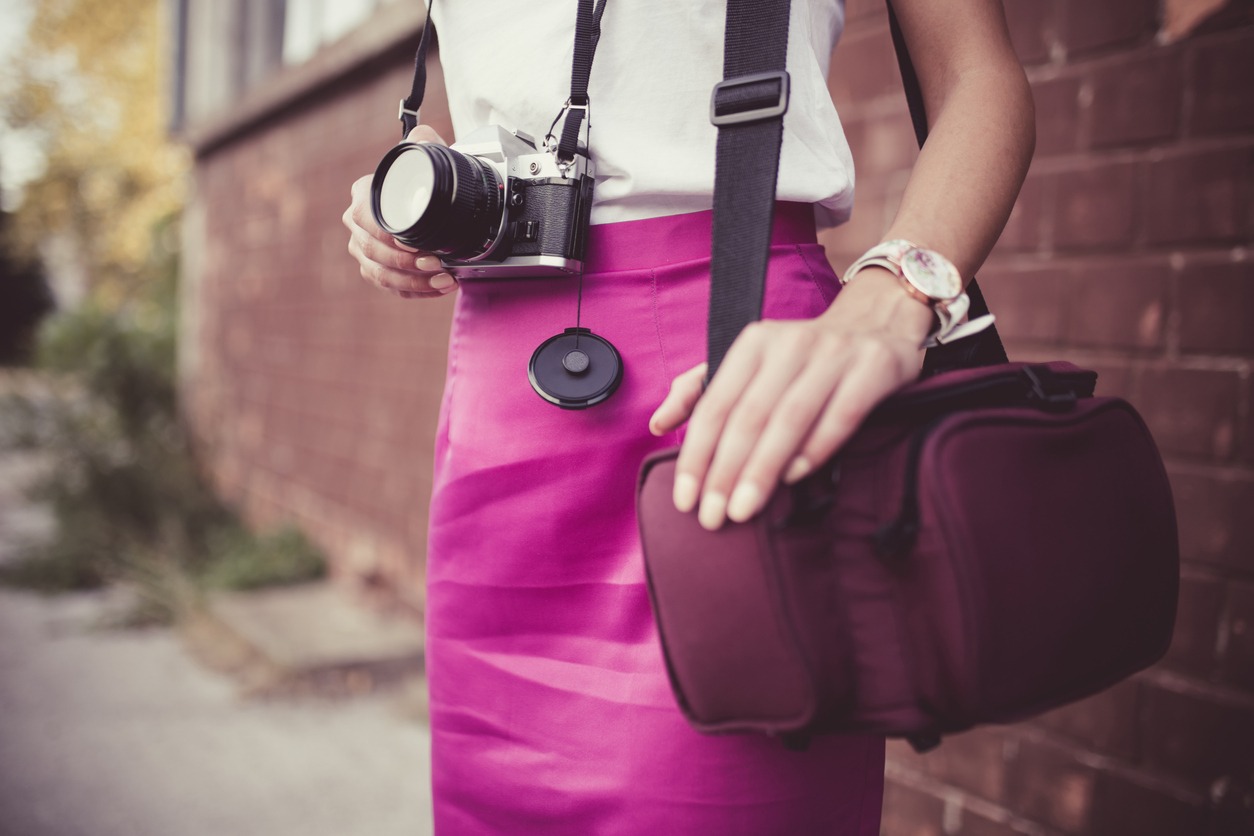 a woman holding a camera and wearing a camera bag