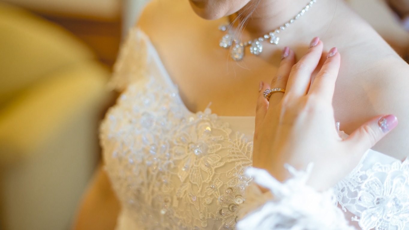 The bride in a white dress and her hand with a wedding ring worn on her finger