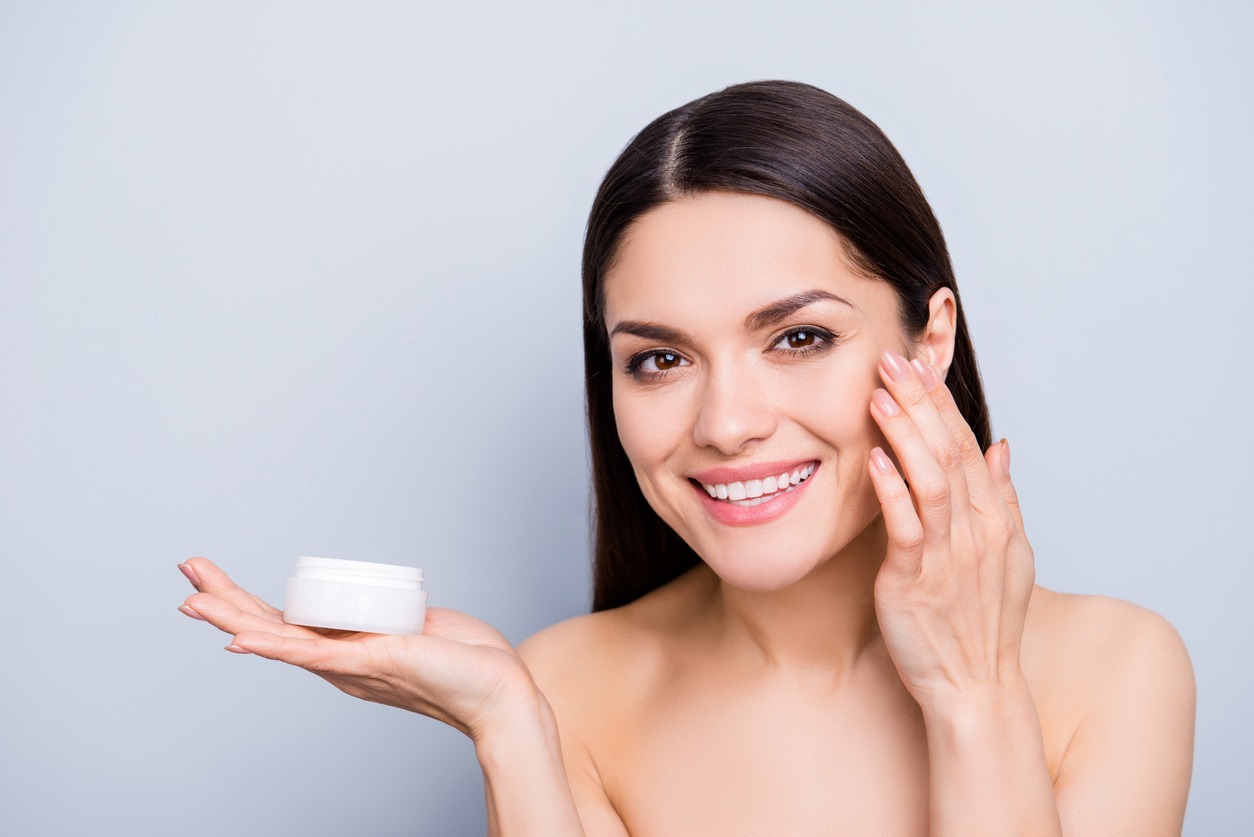 Enhancement perfection rejuvenation revitalization moisturizing concept. Portrait of pretty woman presenting face cream in white jar on palm applying mask for flawless skin isolated on grey background