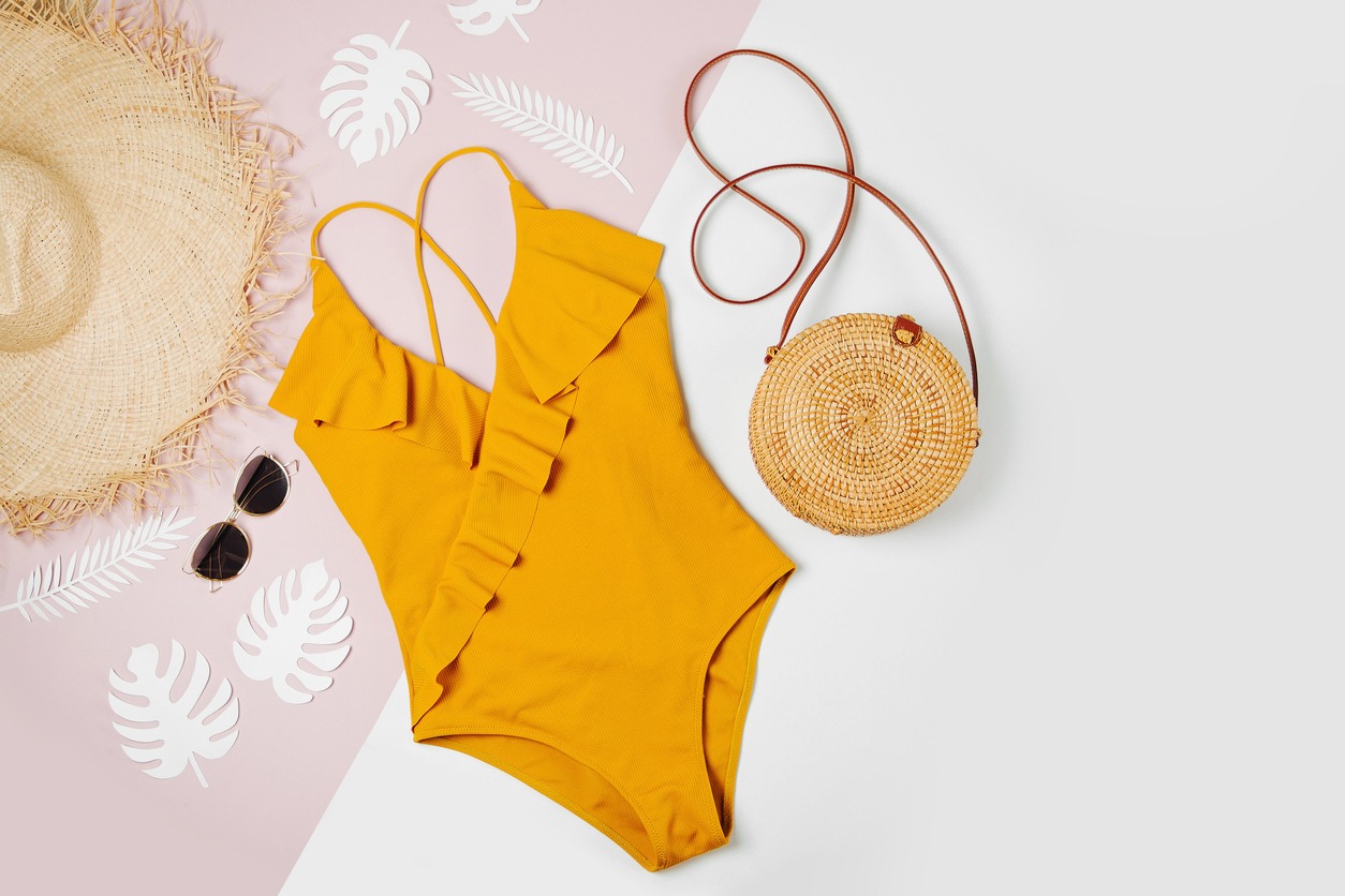 Fashion bamboo bag and sunglass, straw hat, and swimsuit. Flat lay, top view. Summer Vacation concept