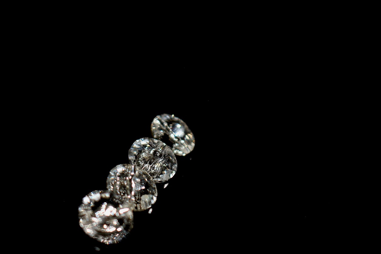 four Swarovski beads. Diamond, crystal beads. Shining. Copy space. Black background. Horizontal image