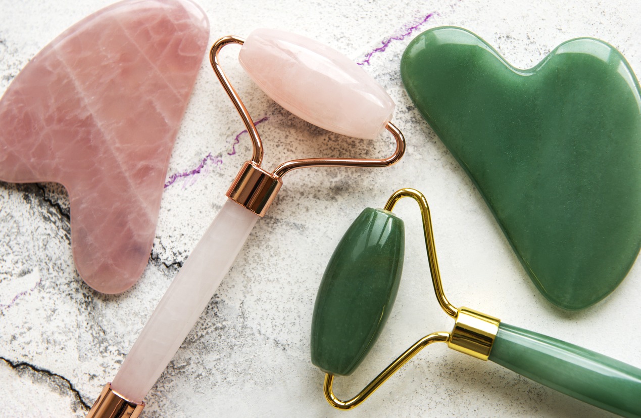 Jade face rollers for beauty facial massage therapy. Flat lay on marble background