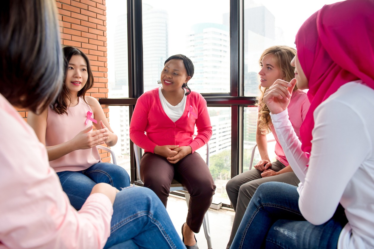 Multiethinic casual women wearing pink color clothes with ribbons meeting for breast cancer awareness campaign