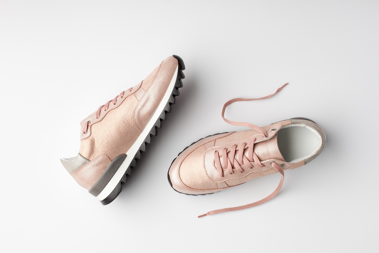 Pastel pink female sneakers on white background. Flat lay,