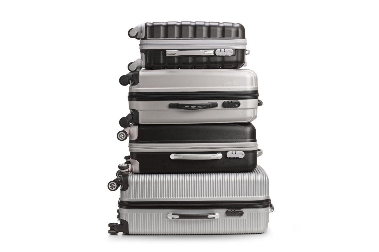Grey and black suitcases stacked together, isolated on a white backdrop.
