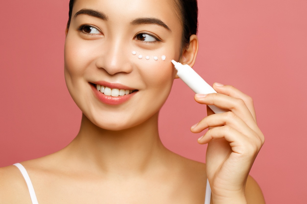 Young woman applying eye lifting cream. Asian beauty model concept