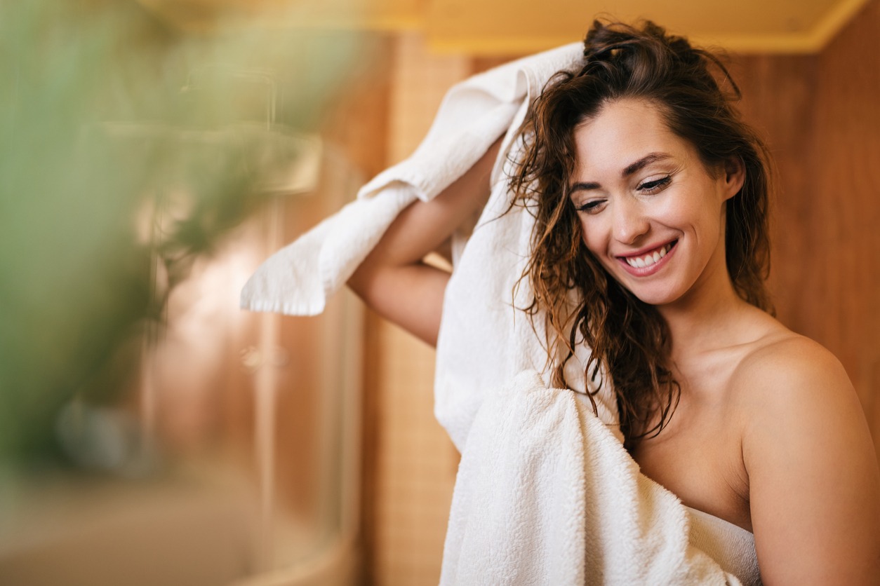 Beautiful happy woman drying her hair with a towel in the bathroom
