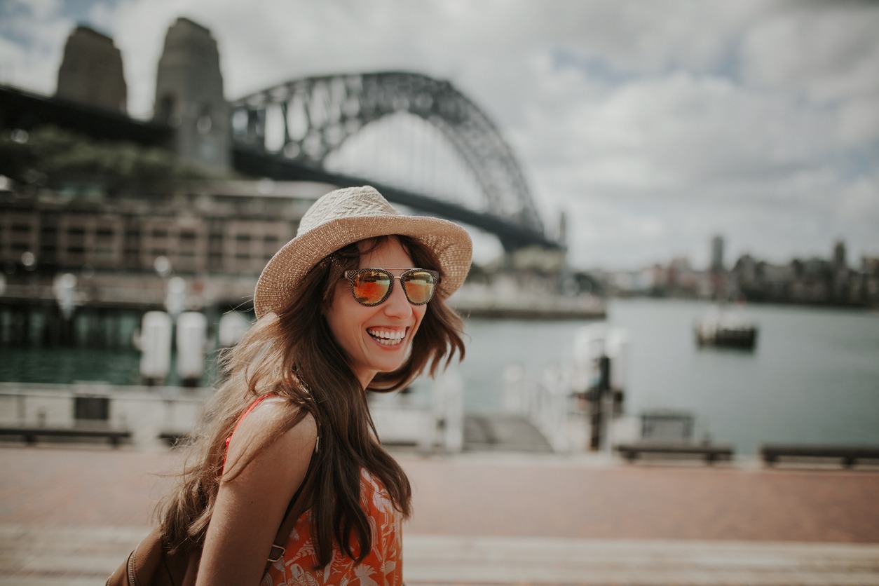 Smiling girl in hat and sunglasses posing in Sydney Harbour