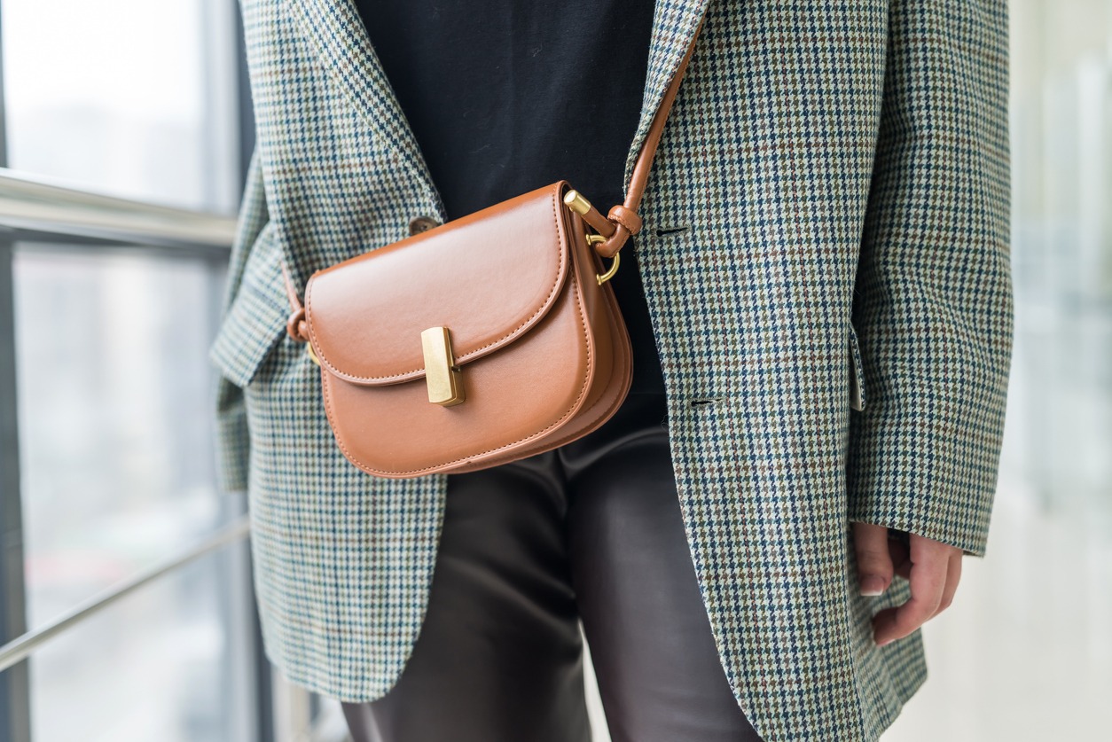 stylish beautiful young woman in elegant clothes with a brown leather handbag on a strap