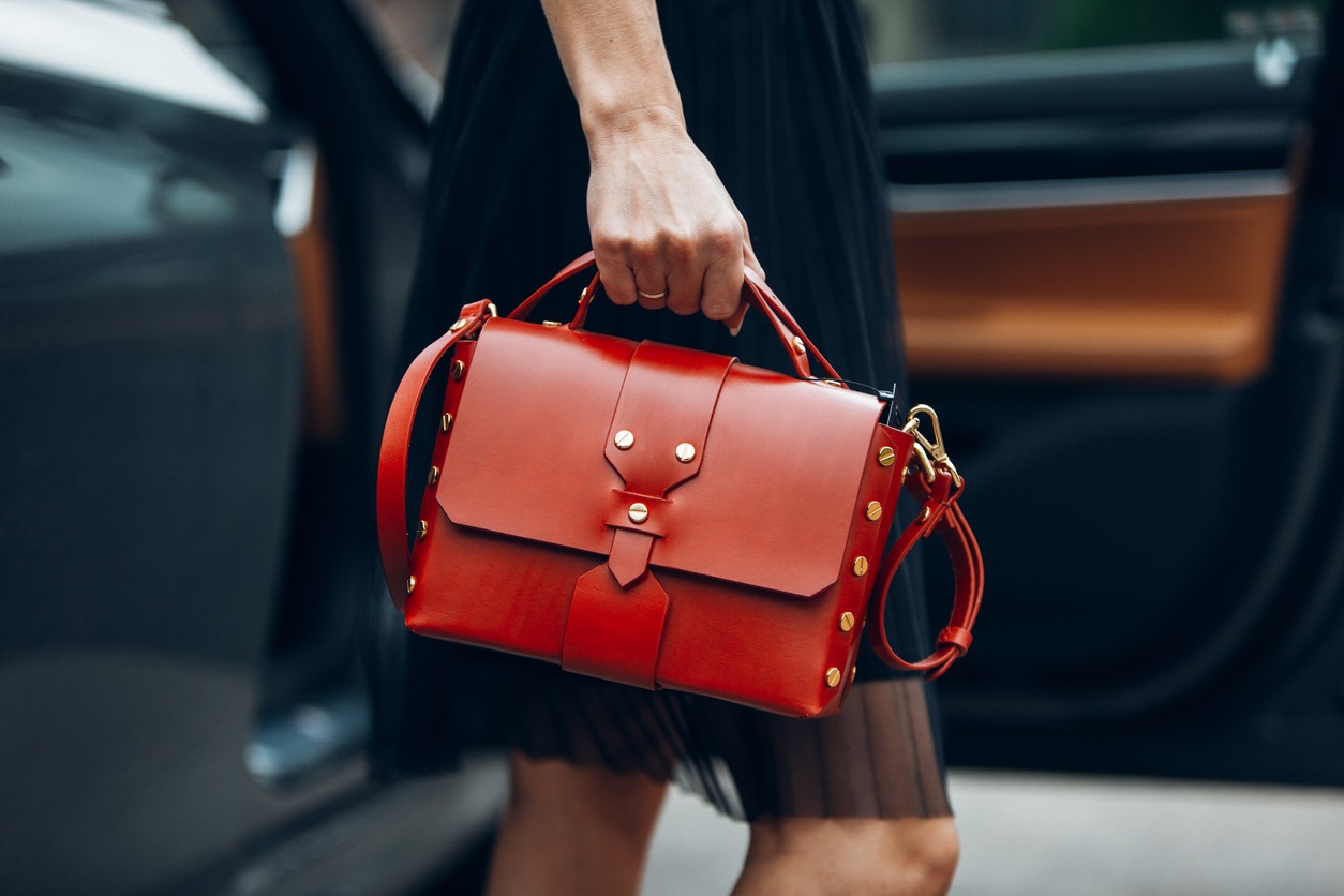 Women is holding handbag near luxury car
