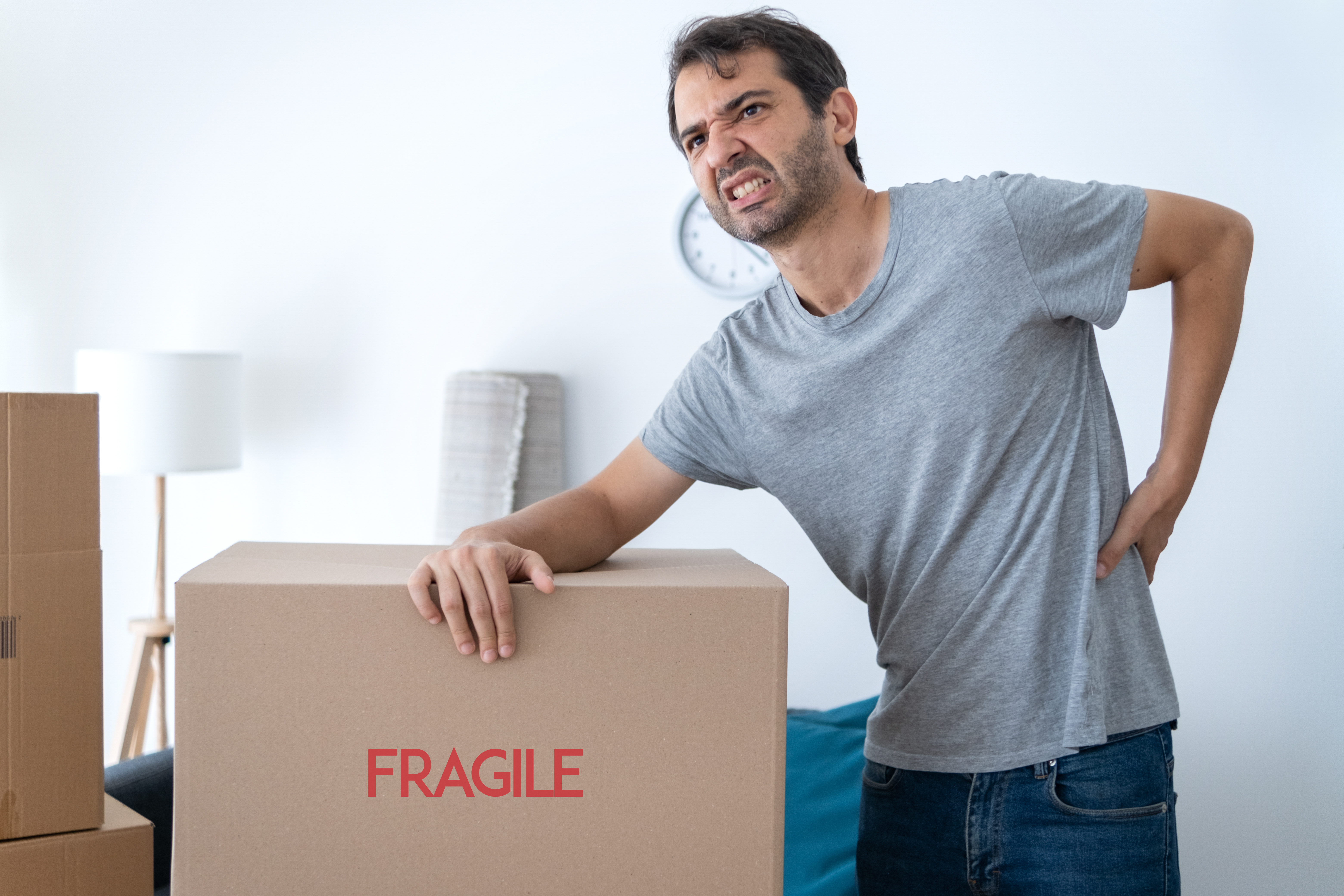 man suffering from back pain after living a big box