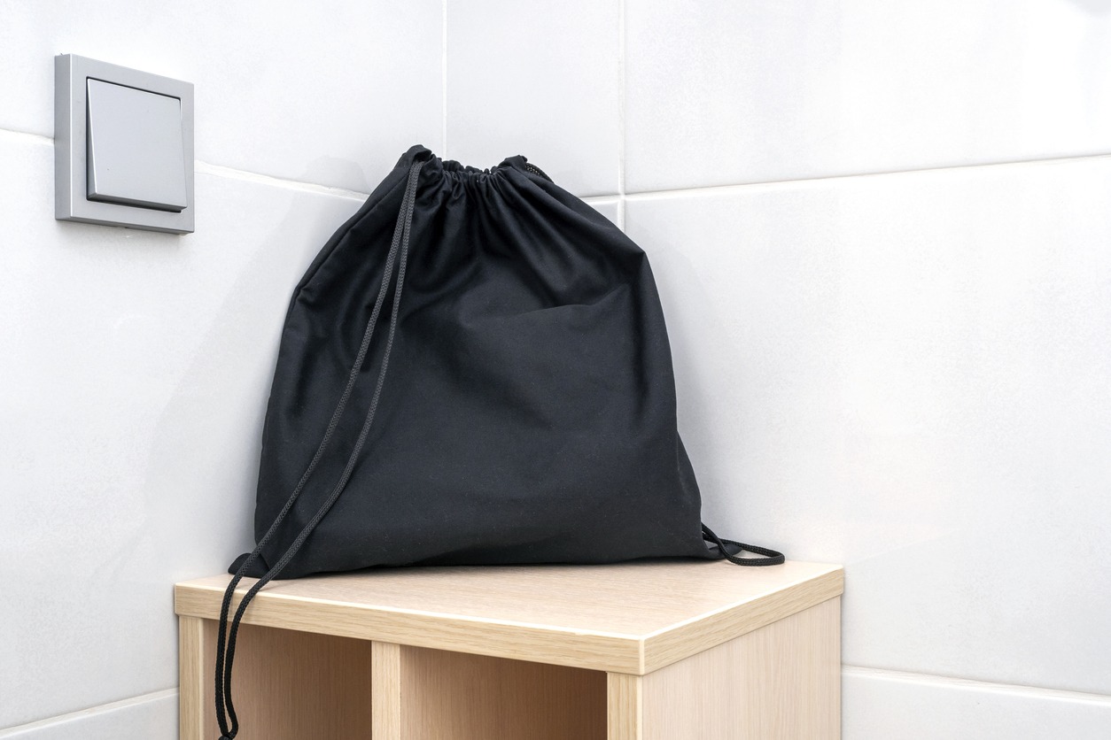 Black fabric bag on a shelf at a bathroom, bag for keeping accessories, hair dryer