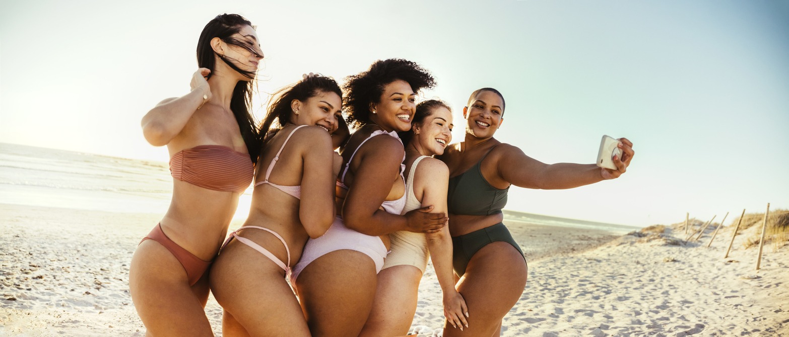 Making memories at the beach. Group of carefree young women smiling cheerfully while taking a picture together in the sun. Happy female friends having fun and enjoying their summer vacation.