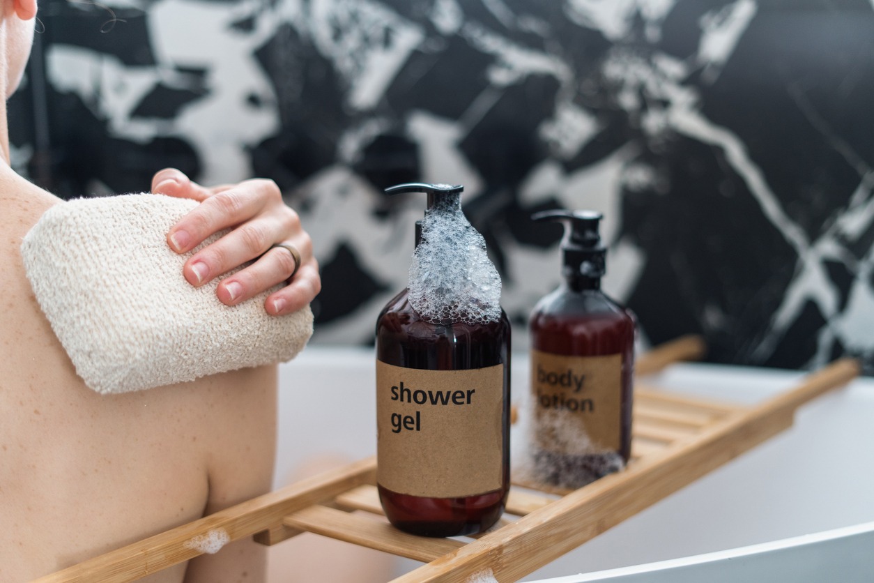 A female back and hand with soft bath sponge applying shower gel