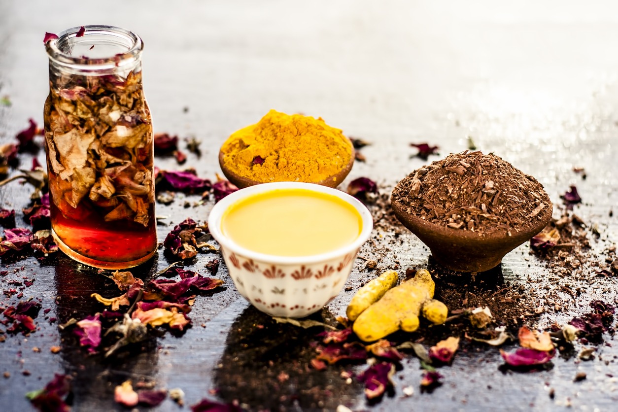 Ayurvedic face pack of chandan, with raw turmeric, sandal wood powder and rose petals on wooden surface